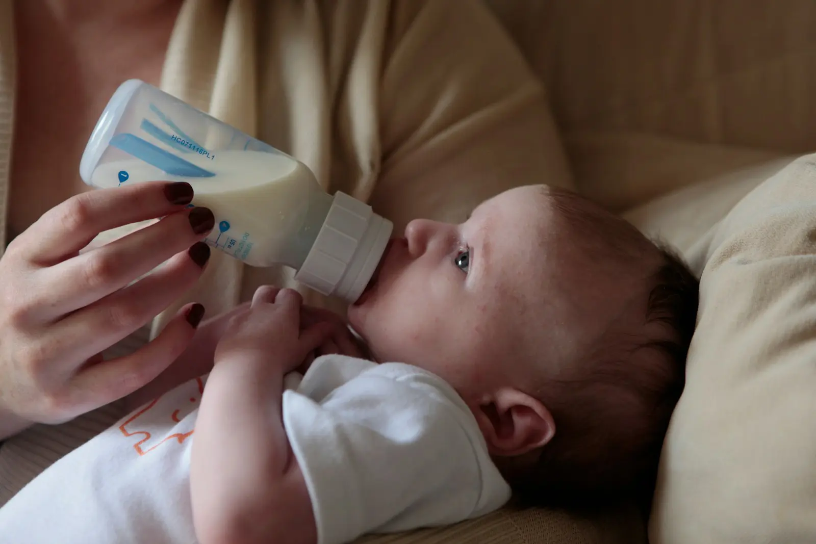 Photo by Lucy Wolski a woman feeding a baby with a bottle of milk