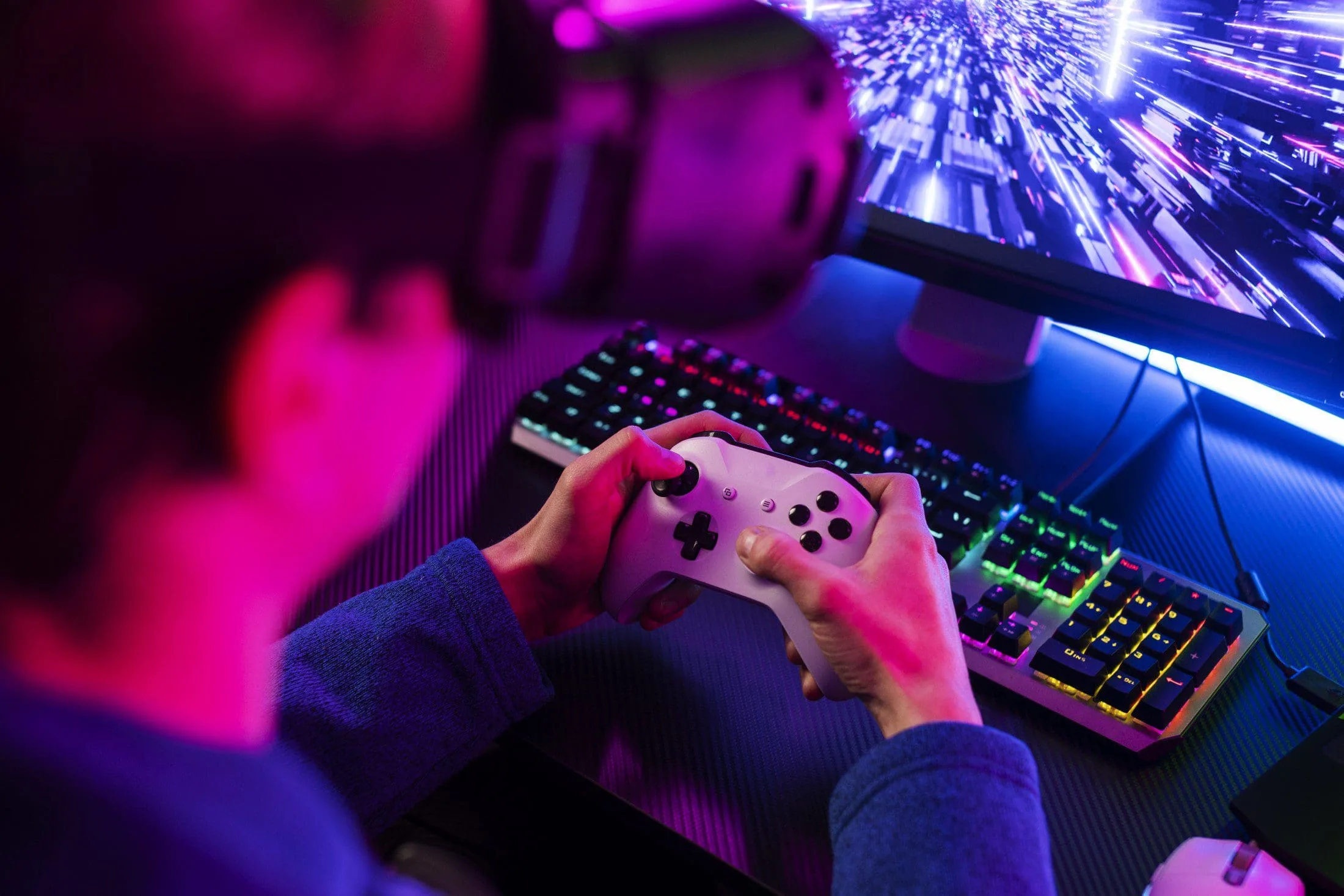 Person playing a video game with a controller under neon lights