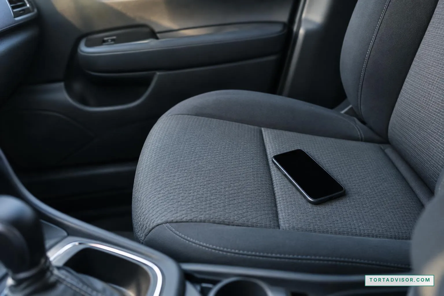 Phone with a blank screen on a parked car's passenger seat, illustrating texting while driving negligence
